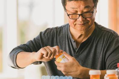 Photo of senior man organizning his medications in his weekly pillbox.