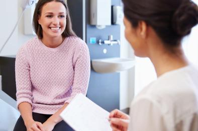 Young woman talkng with doctor at her annual wellness exam.