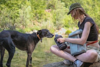 Young woman and her dog by a stream.