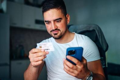 Adult man holding health insurance member ID card.