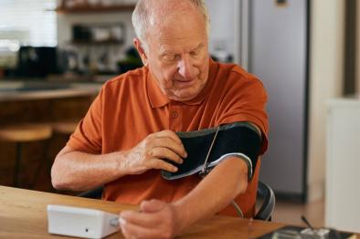 Senior man taking his own blood pressure reading at home.