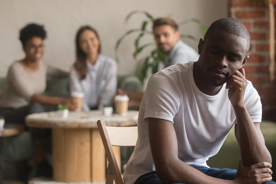 Man sitting alone with 3 people sitting in the distance