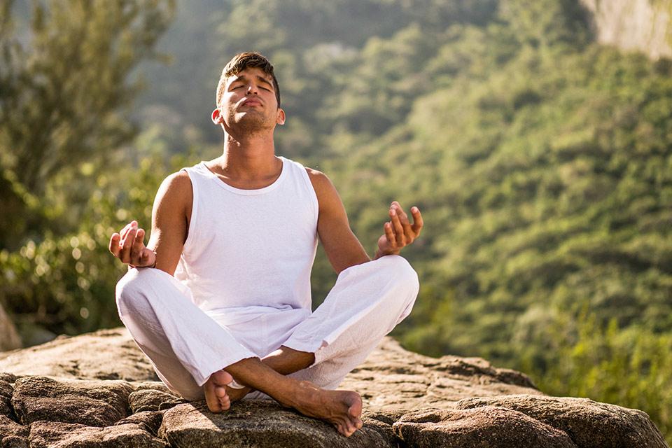 man doing yoga on rock