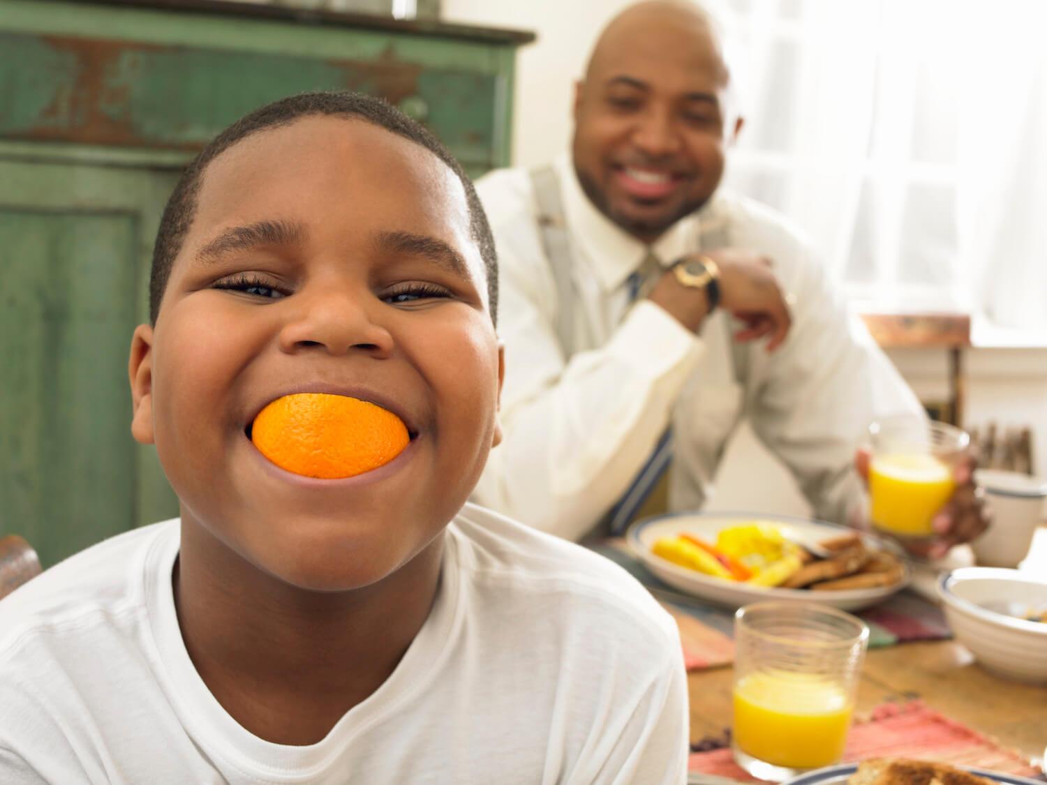 Little boy eating orange.