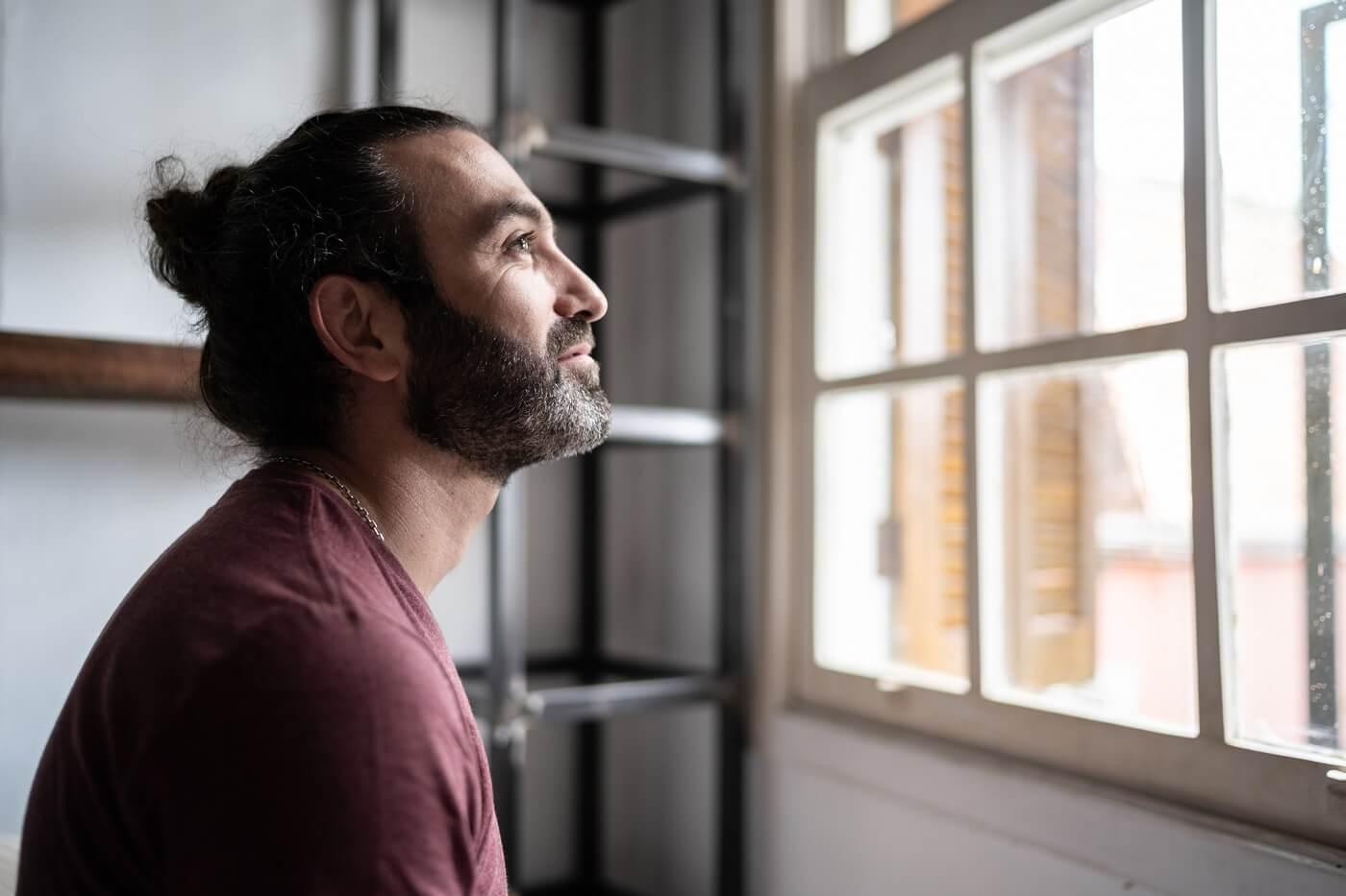 Photo of man looking out window thoughtfully.