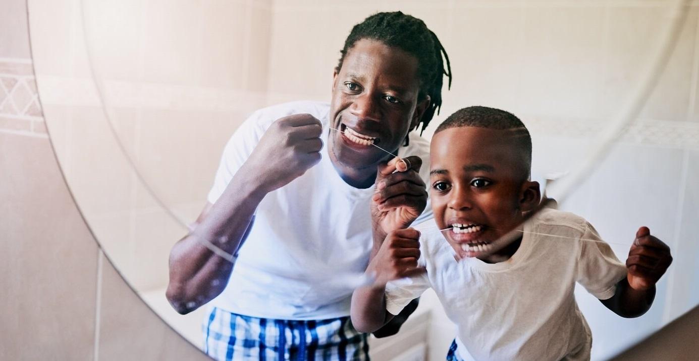 Father and son flossing teeth together.