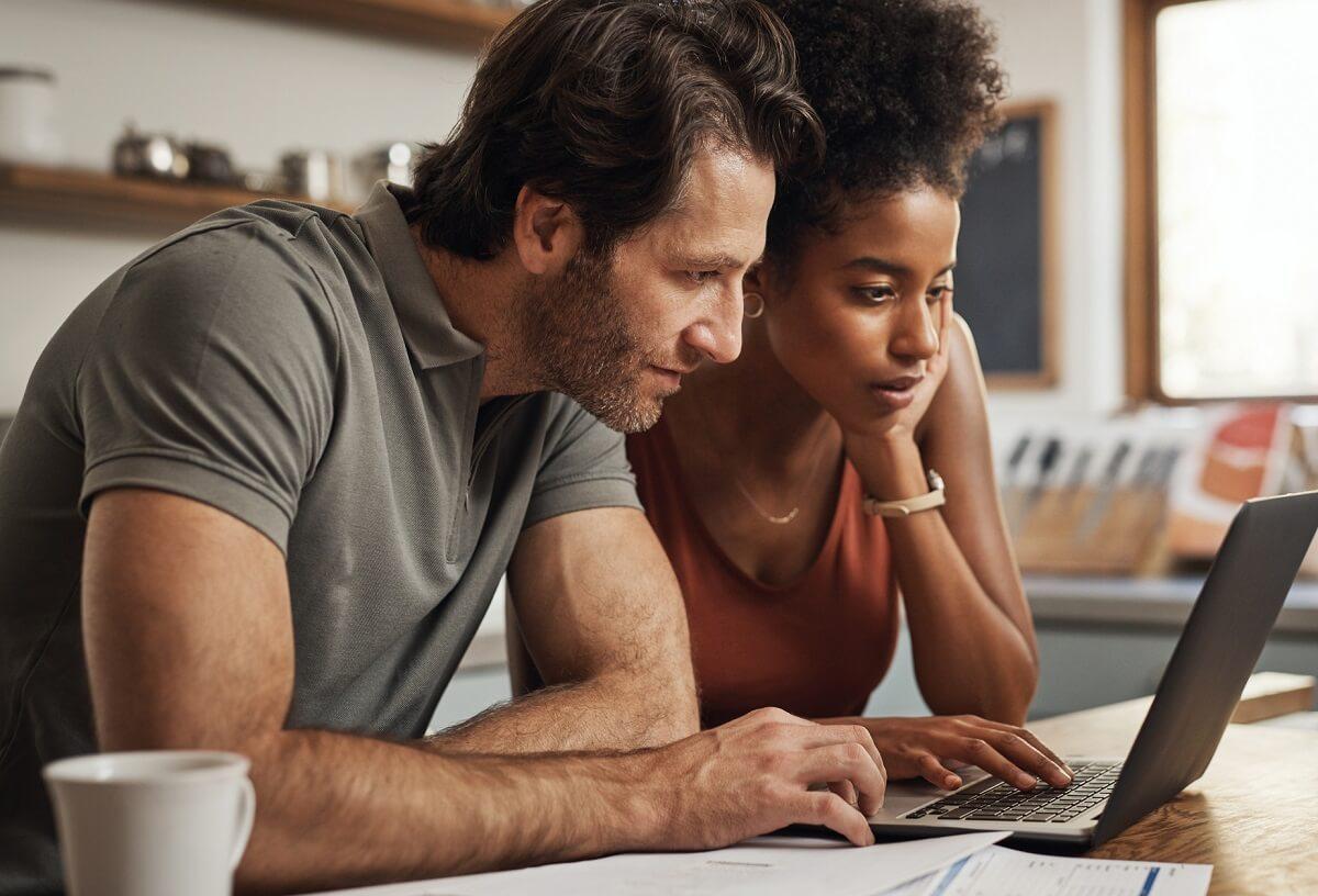 Photo of couple looking intently at laptop screen.