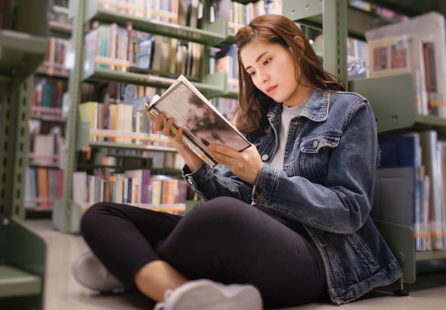Photo of young woman reading at the library
