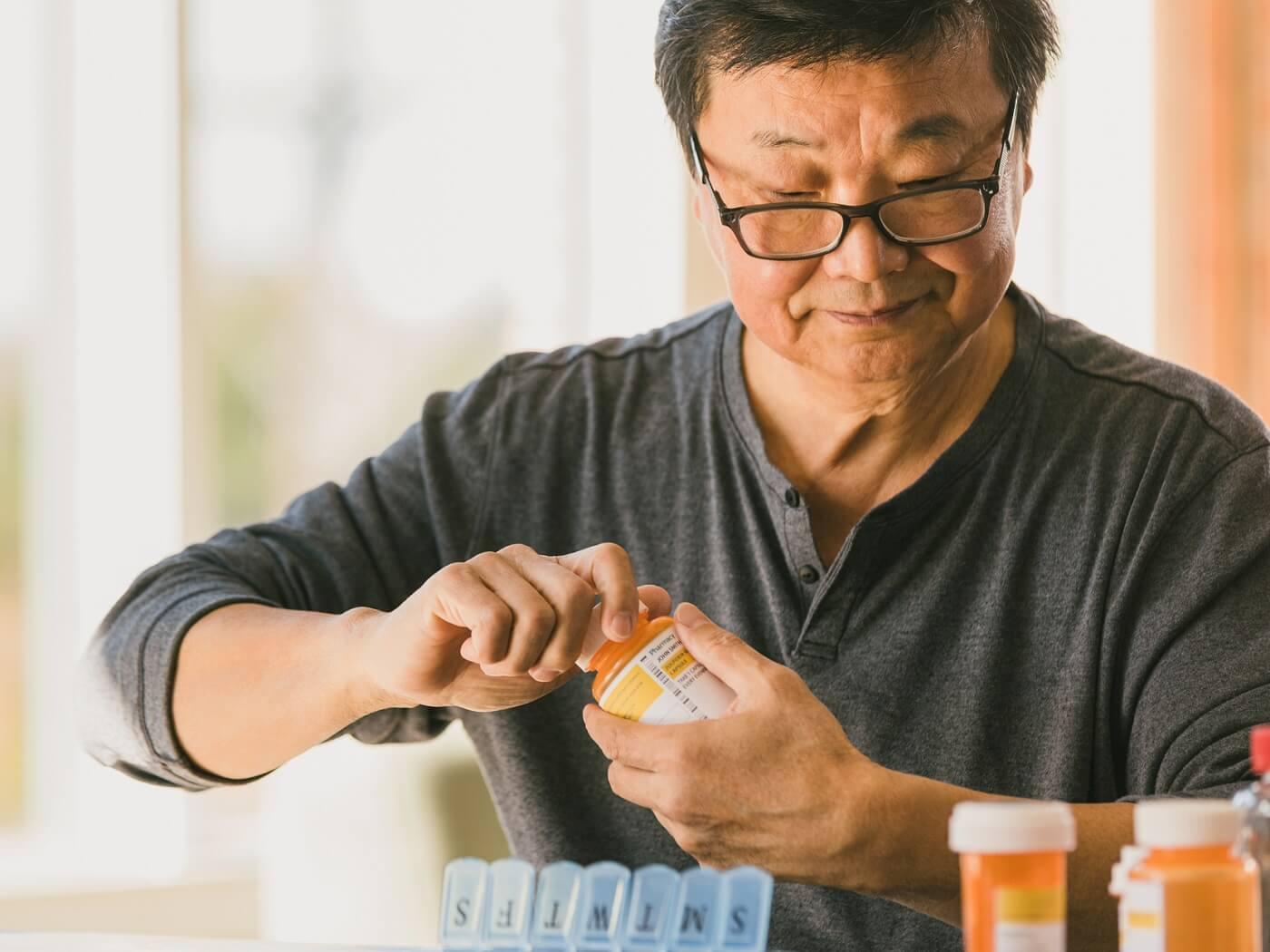 Photo of senior man organizning his medications in his weekly pillbox.