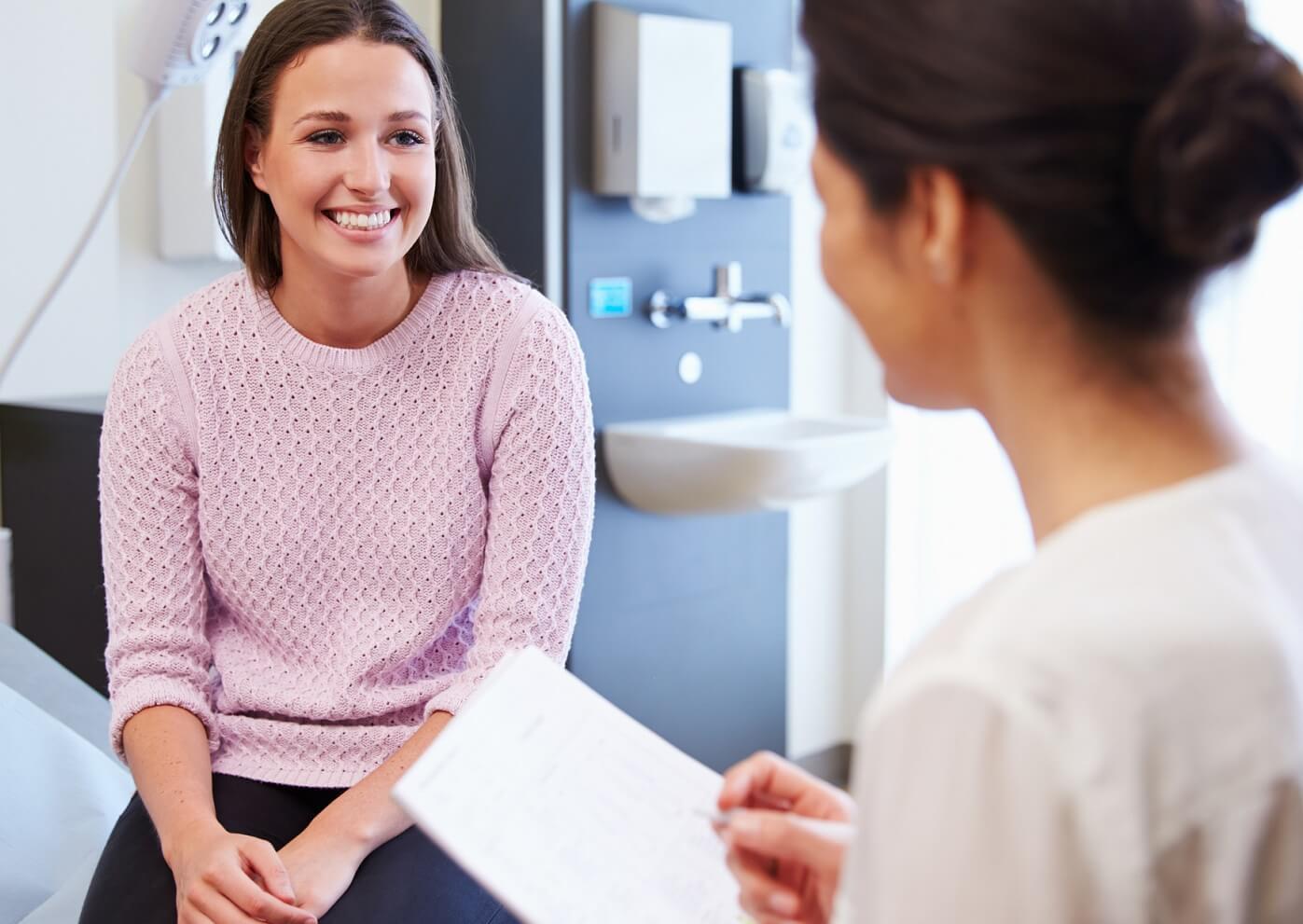 Young woman talkng with doctor at her annual wellness exam.