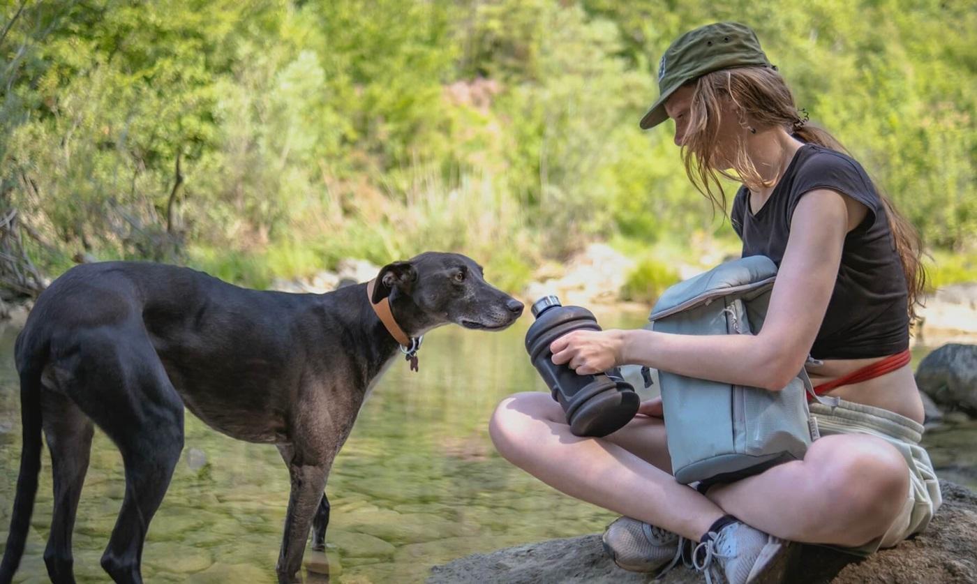 Young woman and her dog by a stream.