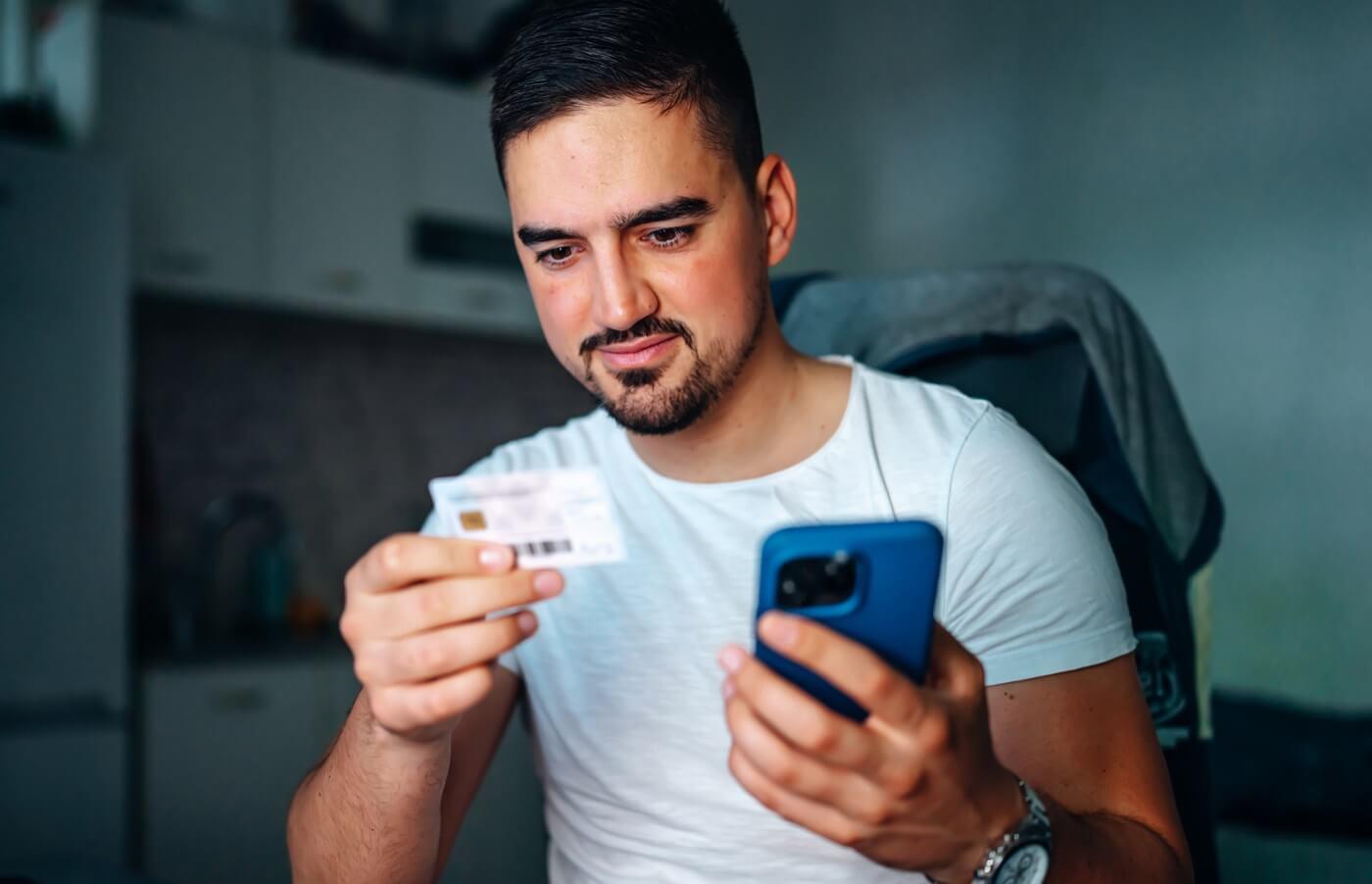 Adult man holding health insurance member ID card.
