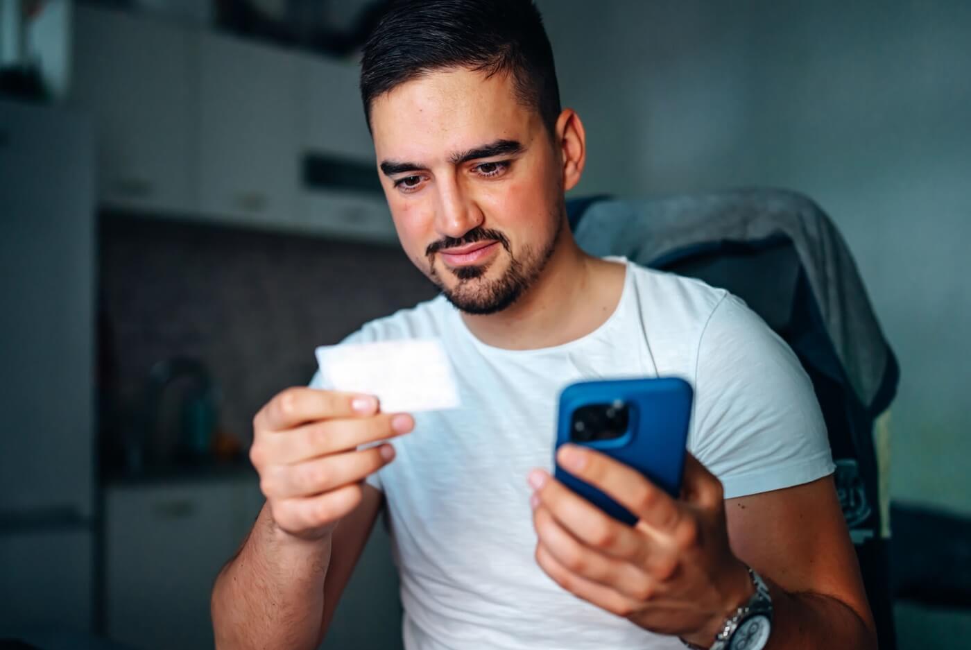 Adult man holding health insurance member ID card.